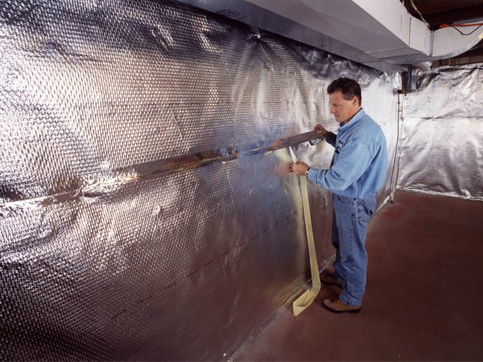 Installation of a radiant heat and vapor barrier on a basement wall in Fairchild Air Force Base